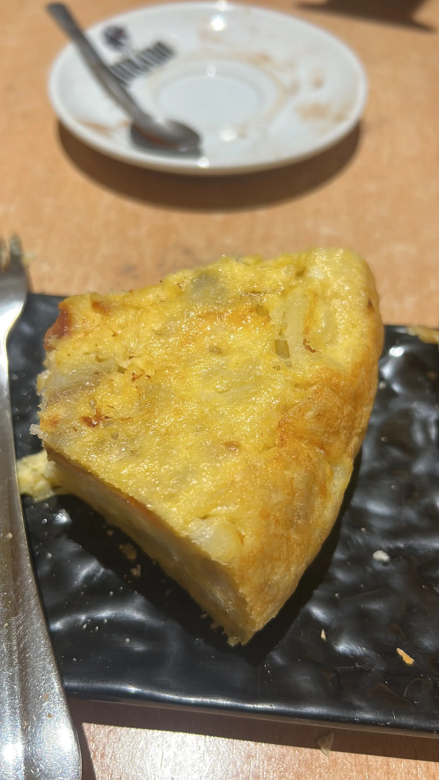 Una porción de tortilla de patatas en un plato negro